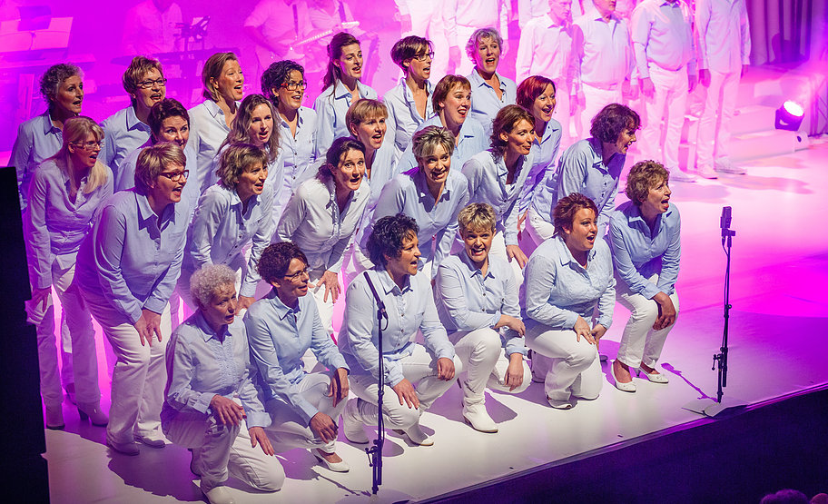 Show Made in holland; dames zingen links voor op het podium, ze zitten hierbij op de knieen